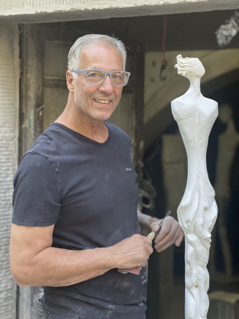 Sculptor John Raffanello standing with a sculpture at his studio in Cortona, Italy